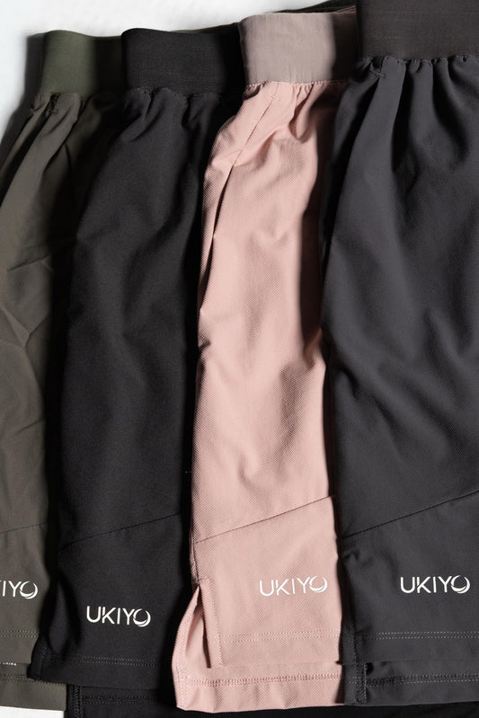 Three pairs of shorts in black, pink, and gray with 'UKIYO' branding on a light gray background.